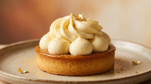 Tartelette gourmande garnie d'une chantilly mascarpone montée à la poche à douille et décorée de feuilles d'or.