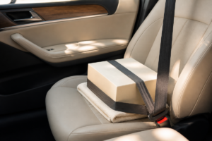 Boîte à gâteau calée à plat sur un siège de voiture, prête pour transporter un dessert sans casse.